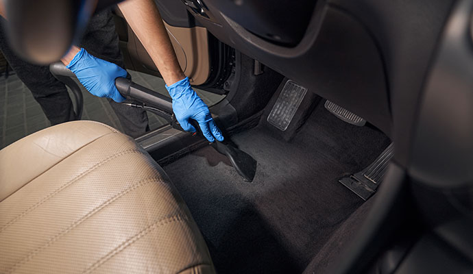 Professional deep clean the dark carpet floor of a vehicle